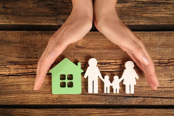 Hands protecting a model home and family